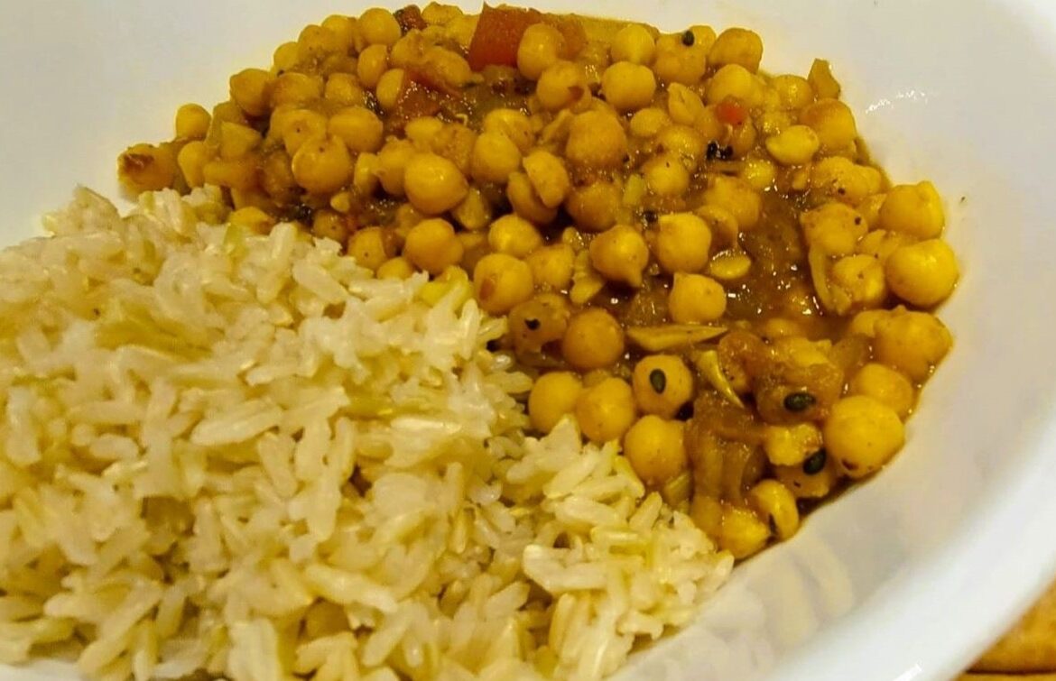 One-pot chickpea curry stew served in a white porcelain bowl alongside brown rice.