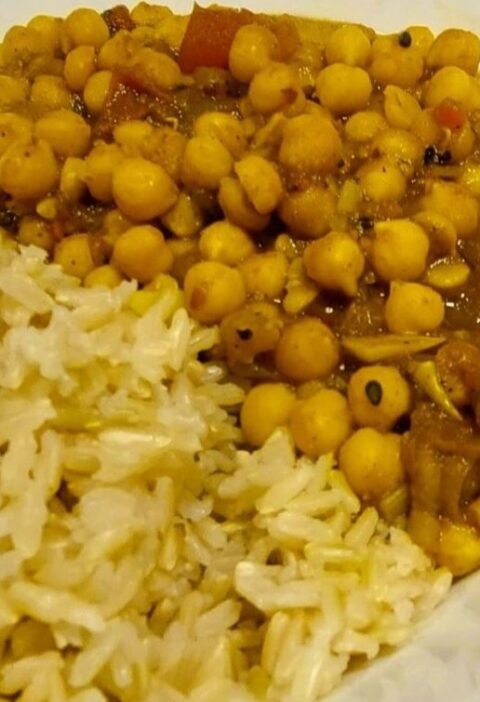 One-pot chickpea curry stew served in a white porcelain bowl alongside brown rice.