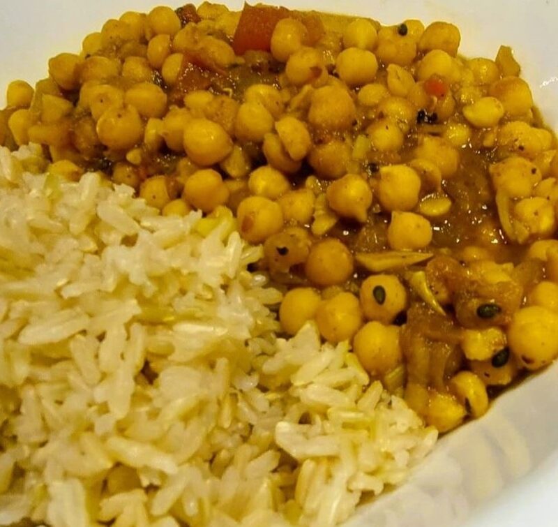 One-pot chickpea curry stew served in a white porcelain bowl alongside brown rice.