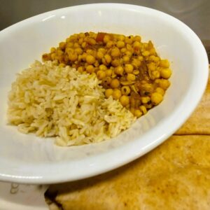 One-pot chickpea curry stew served in a white porcelain bowl alongside brown rice.