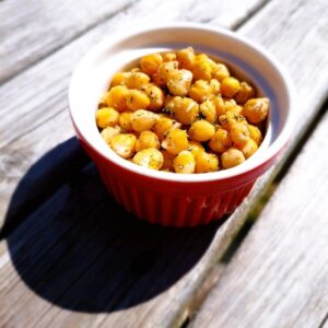 2-Minute Mediterranean Herbed Chickpeas served in a ceramic bowl with red exterior and white interior in the sunshine, garnished with dill and a squeeze of lemon juice.