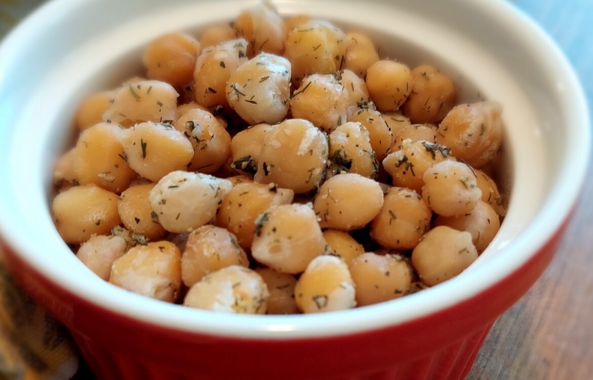 2-Minute Mediterranean Herbed Chickpeas served in a ceramic bowl with red exterior and white interior, garnished with dill and a squeeze of lemon juice.