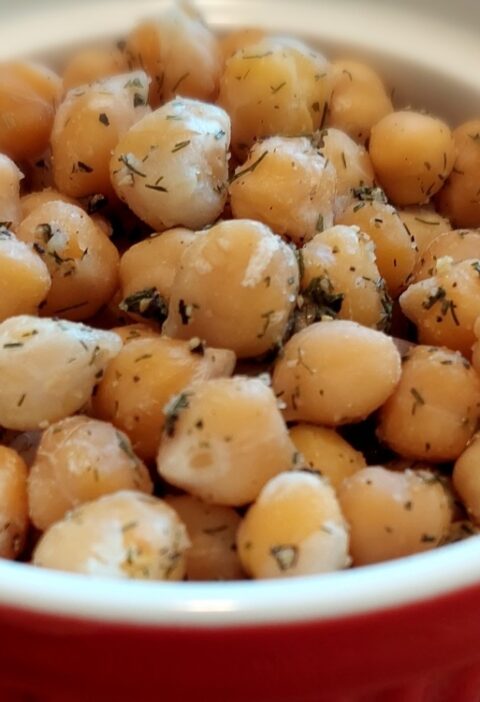 2-Minute Mediterranean Herbed Chickpeas served in a ceramic bowl with red exterior and white interior, garnished with dill and a squeeze of lemon juice.