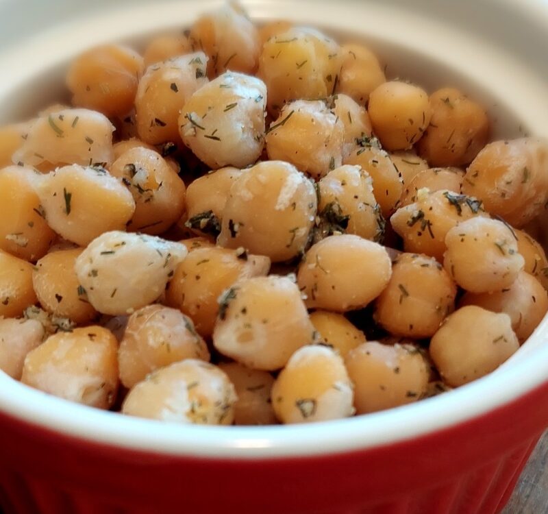 2-Minute Mediterranean Herbed Chickpeas served in a ceramic bowl with red exterior and white interior, garnished with dill and a squeeze of lemon juice.