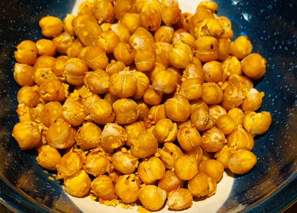 Crispy roasted chickpeas seasoned with herbs in a handmade pottery bowl with dark blue glaze and white details.