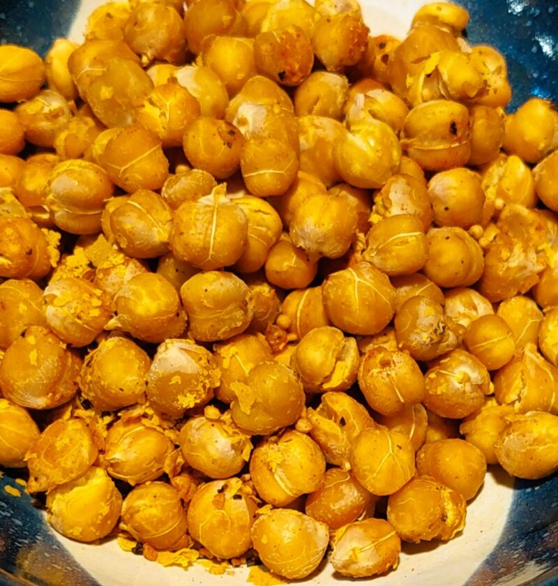 Crispy roasted chickpeas seasoned with herbs in a handmade pottery bowl with dark blue glaze and white details.